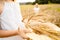 Happy girl in white dress with straw hat full of ears of wheat, rye, barley walking in yellow, orange field. Summer