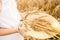 Happy girl in white dress with straw hat full of ears of wheat, rye, barley walking in yellow, orange field. Summer