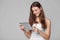 Happy girl in white shirt using tablet. Smiling woman with tablet pc, isolated on grey background