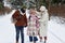 Happy girl in winterwear looking at her mother in white winter coat and hat