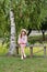 Happy girl on a wooden bench near the birch tree