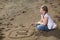 Happy girl writing number in the sand