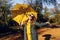 Happy girl, with a yellow umbrella, enjoying the autumn warmth in the Park