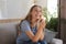 Happy girlfriend looks at engagement ring after proposal sitting on a couch in the living room at home