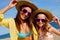 Happy girlfriends on beach with hats and sunglasses.