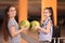 Happy girls with balls in bowling