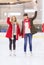 Happy girls friends waving hands on skating rink