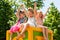 Happy girls raising arms together in park.