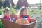 Happy girls sitting inside wheelbarrow at field pumpkin patch