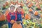 Happy girls standing near big pumpkin at farm field patch