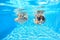 Happy girls swim underwater in pool