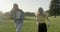 Happy girls teenagers running on grass, green lawn, sunset landscape summer park background