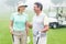 Happy golfing couple facing each other with golf buggy behind