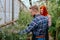 Happy in a good mood gardener lady and her colleague man with a beard in a large greenhouse they analyzing the condition