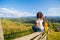 Happy gorgeous girl enjoy hills view sitting in flower field on the hill with breathtaking nature landscape