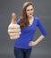 Happy gorgeous young woman agreeing with a large thumbs up