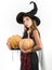 Happy gothic young woman in witch halloween costume with hat standing and smiling over white background. Beautiful