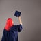 Happy graduate on a gray background. A young woman with bright hair.