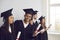 Happy graduate holding diploma and looking at camera, standing in row with other students