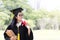 Happy graduate young Asian woman in cap and gown holding a book and certificated in hand, Education concept