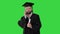Happy graduated young man in cap and gown talking with a friend on mobile phone on a Green Screen, Chroma Key.