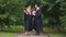 Happy graduates holding diplomas and talking in park after graduation ceremony