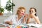 Happy grandchild with grandmother having fun, drawing colored pencils, sitting together at home, laughing preschool girl