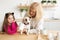 Happy granddaughter and grandmother in the kitchen with jack russell terrier dog. Grandma and grandchild spend time