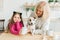 Happy granddaughter and grandmother in the kitchen with jack russell terrier dog. Grandma and grandchild spend time