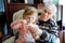 Happy grandfather and cute little toddler granddaughter, adorable child eating together ice cream. Family tasting sweet