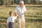 Happy grandfather and grandson walking at summer meadow.  Cute boy gives flowers his old grandpa