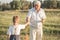 Happy grandfather and grandson walking at summer meadow.  Cute boy gives flowers his old grandpa