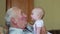 Happy grandfather holds a baby on hands and kissing