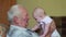 Happy grandfather holds a baby on hands and talking