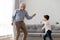 Happy grandfather and little grandchild dancing to music together