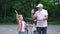 Happy grandfather teaching boy how to ride bicycle at summer park. family, generation, safety and people concept