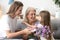 Happy grandma thanking grandchild and grown daughter for flowers