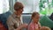 Happy grandmother braiding pigtail for granddaughter at home. Smiling family