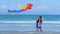Happy grandmother with child the playing flying kite, the family runs on the sand of a tropical ocean playing with the