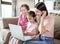 Happy grandmother with little kid and daughter having fun online with laptop at home