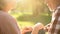 Happy grandparents looking at each other with love, resting on grass in park