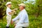 Happy grandson, and grandpa having fun in spring garden, blowing dandelions