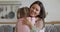 Happy grateful young mom embrace kid daughter holding flowers bouquet