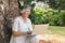 Happy grey haired woman with a laptop sitting on tree