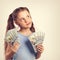 Happy grimacing fun thinking kid girl holding money in the hands