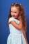 Happy grimacing kid girl posing in blue fashion dress. Closeup p