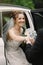 Happy groom helping his beautiful bride out of the wedding car.