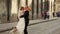 Happy groom holds in arms and kisses his bride in the city center