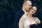 Happy groom hugging beautiful bride in white wedding dress and red flowers bouquet from behind, happy newlywed couple moment