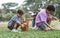 Happy group of diverse cute children hunting Easter eggs, girl wearing bunny ears. kids holding basket, picking eggs on grass